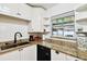 Corner kitchen features white cabinets, granite countertops, and a window view at 4610 W Mcelroy Ave, Tampa, FL 33611