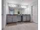 Bathroom featuring double sinks, gray countertops, ample storage space, and a tiled shower with glass doors at 5068 Little Stream Ln, Wesley Chapel, FL 33545