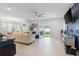 Bright living room with tile flooring, plush sofa, ceiling fan, and sliding glass doors to the backyard at 5068 Little Stream Ln, Wesley Chapel, FL 33545