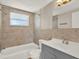 Well-lit full bathroom with neutral stone tiling, shower and tub combo, and vanity at 6017 6Th Ave, New Port Richey, FL 34653