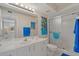 Bright bathroom featuring white cabinetry, walk-in shower with blue accents, and nautical-themed artwork at 6081 Bahia Del Mar Cir # 452, St Petersburg, FL 33715