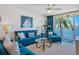 Bright living room with blue furnishings, coastal decor, and water views from sliding glass doors to balcony at 6081 Bahia Del Mar Cir # 452, St Petersburg, FL 33715