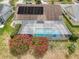 Aerial view of the backyard with screened in pool and landscaped yard at 9253 Water Hazard Dr, Hudson, FL 34667