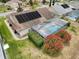 Aerial view of home showcasing solar panels and a screened-in pool surrounded by vibrant landscaping at 9253 Water Hazard Dr, Hudson, FL 34667