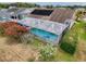 Aerial view of a home featuring solar panels, a screened-in pool, and mature landscaping at 9253 Water Hazard Dr, Hudson, FL 34667