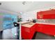 Bright kitchen features stainless steel appliances, modern red cabinets, granite countertops and barstool seating at 9253 Water Hazard Dr, Hudson, FL 34667