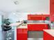 Bright kitchen features stainless steel appliances, modern red cabinets, granite countertops, and barstool seating at 9253 Water Hazard Dr, Hudson, FL 34667