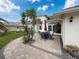 Home's front patio featuring a stylish table with chairs and a unique central palm tree at 9253 Water Hazard Dr, Hudson, FL 34667