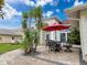 Outdoor patio with seating area, lush landscaping, and a red umbrella for shade at 9253 Water Hazard Dr, Hudson, FL 34667