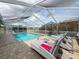 This inviting pool area features a screened enclosure, comfortable lounge chairs, and flowering bushes creating a private retreat at 9253 Water Hazard Dr, Hudson, FL 34667