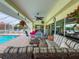Pool area with a covered patio, dining set, wicker seating, and serene pool views at 9253 Water Hazard Dr, Hudson, FL 34667