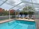 Picture perfect screened pool area with an umbrella and lounge chairs surrounded by lush bushes at 9253 Water Hazard Dr, Hudson, FL 34667