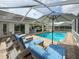 Relaxing screened pool area features a shimmering pool, sun loungers and an umbrella for comfortable outdoor living at 9253 Water Hazard Dr, Hudson, FL 34667