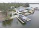 Aerial view of a waterfront home with solar panels, dock with boat lift, and lush tropical landscaping at 9914 Alavista Dr, Gibsonton, FL 33534