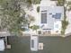 Aerial of waterfront home showcasing solar panels, dock with lift, outdoor dining, lush landscaping, and boat trailer parking at 9914 Alavista Dr, Gibsonton, FL 33534