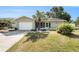 Charming single-story home with a well-manicured lawn, palm tree and a two-car garage at 1003 Carol Ann Pl, Dunedin, FL 34698