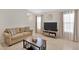 Cozy living room featuring neutral tones, a comfortable sofa, modern entertainment center, and bright natural light at 10360 Honeysuckle Vine Cir, Riverview, FL 33578
