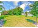 Large green backyard showing an enclosed tennis court in the distance at 1137 King Arthur Ct # 501, Dunedin, FL 34698