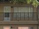 Close-up of a unit with a white door, dark railings, and large window with vertical blinds at 1257 Drew St # 15, Clearwater, FL 33755
