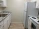 Galley kitchen featuring white appliances, granite-style countertops, and wood-look vinyl flooring at 1257 Drew St # 15, Clearwater, FL 33755