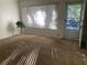 Bright living room with neutral carpet, white walls, vertical blinds, and a door to the outside at 1257 Drew St # 15, Clearwater, FL 33755