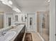 Bathroom with dual sinks, granite countertop, large mirror, walk-in shower, and ample lighting at 12669 Eastpointe Dr, Dade City, FL 33525