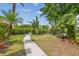 Tranquil backyard with lush landscaping, paver path, and direct water access at 1326 Apollo Beach S Blvd, Apollo Beach, FL 33572
