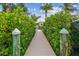 Inviting wooden walkway leads to a private dock, surrounded by lush greenery and a glimpse of the house at 1326 Apollo Beach S Blvd, Apollo Beach, FL 33572