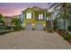 Inviting yellow two-story home with colorful shutters, a two-car garage, and lush landscaping at 1326 Apollo Beach S Blvd, Apollo Beach, FL 33572