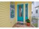 Charming turquoise front door with decorative glass panel, bright yellow siding, and a welcoming doormat at 1326 Apollo Beach S Blvd, Apollo Beach, FL 33572