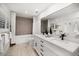 A bathroom features a dual sink vanity with updated fixtures, a tub, and wood-look flooring at 16 Hibiscus Rd, Belleair, FL 33756