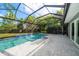 A screened-in pool area features a swimming pool with tile accents, waterfall feature and open-air patio at 16 Hibiscus Rd, Belleair, FL 33756