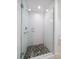 Walk-in shower with glass enclosure and rain shower head features neutral tile and pebble flooring at 16 Hibiscus Rd, Belleair, FL 33756
