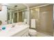 Bathroom featuring a sink and mirror, toilet, and glass enclosed shower with tiled walls at 17900 Gulf Blvd # 1B, Redington Shores, FL 33708