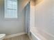 Bathroom featuring a white tiled shower/tub and window with natural light, simple and functional at 18203 Pine Hammock Blvd, Lutz, FL 33548
