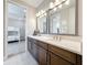 Modern bathroom with a double vanity featuring stone countertops and a view into the bedroom at 18203 Pine Hammock Blvd, Lutz, FL 33548