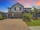 Two-story home featuring a three-car garage, well-manicured lawn, brick paver driveway, and stone accents at 18203 Pine Hammock Blvd, Lutz, FL 33548