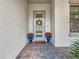 Front door with sidelight windows flanked by blue planters, brick floor, and decorative wreath at 18203 Pine Hammock Blvd, Lutz, FL 33548