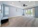 Expansive primary bedroom with a tray ceiling, ceiling fan, and glass doors to a balcony at 18203 Pine Hammock Blvd, Lutz, FL 33548