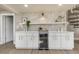 Built-in bar area with white cabinets, gold hardware, wine cooler, and decorative shelving at 1905 Pine Tree Ln, Belleair Bluffs, FL 33770
