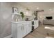 Home bar with white cabinets, gold hardware, wine refrigerator and decorative lighting at 1905 Pine Tree Ln, Belleair Bluffs, FL 33770