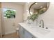 Bathroom featuring double sinks with a large oval mirror and natural light from the window at 1905 Pine Tree Ln, Belleair Bluffs, FL 33770