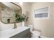 Modern bathroom with a vanity, sink, mirror, toilet, and shower with unique tile accent wall, creating a stylish design at 1905 Pine Tree Ln, Belleair Bluffs, FL 33770