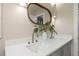 Elegant bathroom featuring a double vanity with modern fixtures and a stylish oval mirror at 1905 Pine Tree Ln, Belleair Bluffs, FL 33770