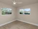 Bright bedroom with ample natural light from two windows and complemented by a ceiling fan at 1905 Pine Tree Ln, Belleair Bluffs, FL 33770