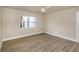 Neutral bedroom featuring hardwood flooring, white trim, a ceiling fan, and a large window for lots of natural light at 1905 Pine Tree Ln, Belleair Bluffs, FL 33770