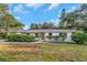 Charming single-story home featuring a well-maintained front lawn and inviting gray front door at 1905 Pine Tree Ln, Belleair Bluffs, FL 33770