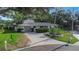 Well-kept home features a circular driveway, lush landscaping, and mature shade trees at 1905 Pine Tree Ln, Belleair Bluffs, FL 33770