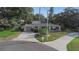 Charming home with a well-manicured front lawn, mature trees, and a circular driveway at 1905 Pine Tree Ln, Belleair Bluffs, FL 33770
