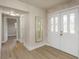 Hallway view showing front doors, wood floors, and open entrance into other rooms at 1905 Pine Tree Ln, Belleair Bluffs, FL 33770